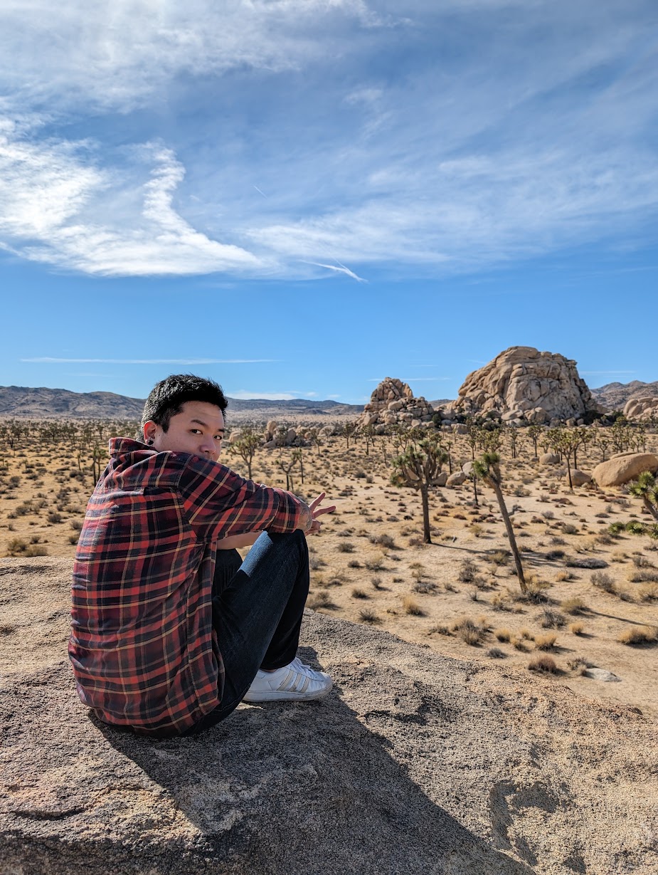 Ben sitting on a rock above a desert landscape.